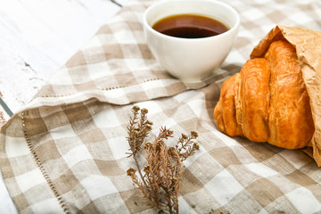 morning with a croissant. the beginning of the morning. Fresh french croissant. Coffee cup and fresh baked croissants on a wooden background. View from above. Morning breakfast with croissant and coff