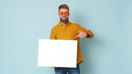 Young man in yellow shirt and sunglasses is holding a white banner.