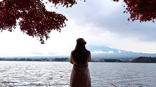 4K Young Asian woman take photo and seeview Fuji Mountain and Maple Leaf red colour in autumn season lake view Lake Kawaguchi,Japan travel concept