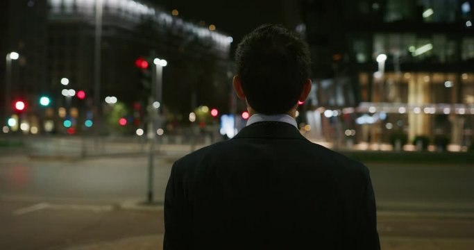 Slow motion of close up of young handsome businessman walking in a busy city center with traffic by night . Shot in 8K. Concept of business and finance, success, monopoly,wall street