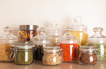 Glass jars with different types of groats on wooden shelf