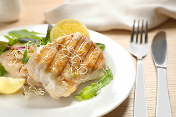 Tasty grilled fish served on wooden table, closeup