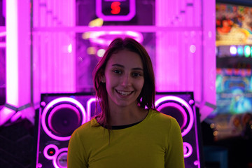 Young and beautiful girl dressed in yellow smiling in an Arcade entertainment center.