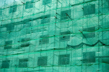 Building structure with green netting shade and scaffolding