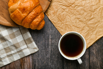 coffee with a croissant. the beginning of the morning. A cup of coffee. fresh french croissant. Coffee cup and fresh baked croissants on a wooden background. View from above.