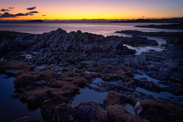 Tranquil sunset scene on rocky beach, on west coast of Scotland.Colourful sky at twilight and puddles of water among rocks during low tide.Beauty in nature.