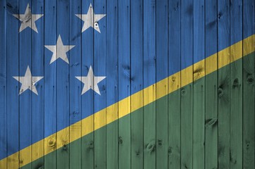 Solomon Islands flag depicted in bright paint colors on old wooden wall. Textured banner on rough...