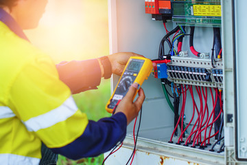 Workers use Multimeter to measure the voltage of electrical wires produced from solar energy for confirm to systems working normal