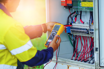 Workers use Multimeter to measure the voltage of electrical wires produced from solar energy for...
