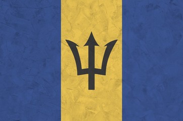 Barbados flag depicted in bright paint colors on old relief plastering wall. Textured banner on...