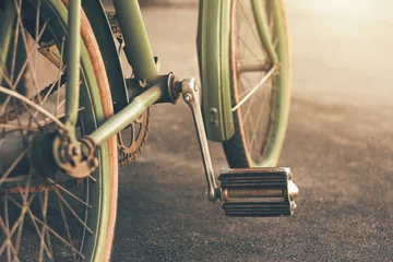 Photo sur Plexiglas Vélo Sur l& 39 asphalte se dresse un vieux vélo rétro vert avec des pièces rouillées et une chaîne, éclairé par une lumière agréable.