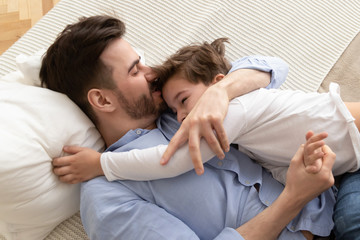 Above view father hugs little son family lying on bed