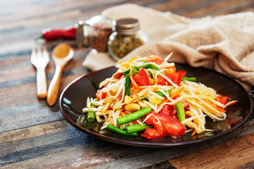 Traditional Thai food papaya salad prepared with fine slices of papaya, tomatoes, green beans and peanuts.