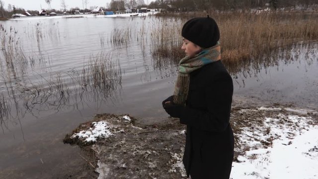 Woman at shore of the lake try to feed ducks