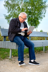 Positive elderly man with glasses on bench