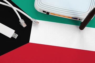 Kuwait flag depicted on table with internet rj45 cable, wireless usb wifi adapter and router....