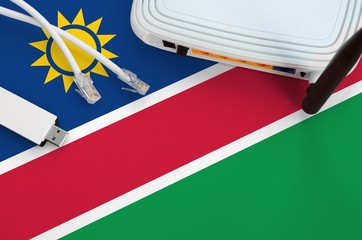 Namibia flag depicted on table with internet rj45 cable, wireless usb wifi adapter and router....