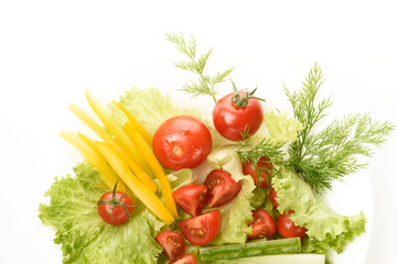 Fresh vegetables lie on the green leaves. Tomatoes, cucumbers, yellow peppers, lettuce isolated on a white background.