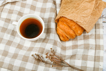 morning with a croissant. the beginning of the morning. Fresh french croissant. Coffee cup and fresh baked croissants on a wooden background. View from above. Morning breakfast with croissant and coff