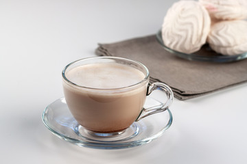 Cup of hot latte coffee with marshmallows on a white table