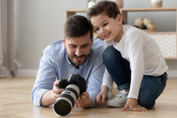 Father holding photocamera explaining teaching little son how take photo
