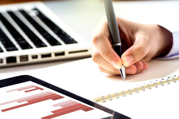 Businessman with digital tablet computer and writing on a notepad