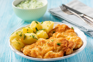 Chop pork cutlets , served with boiled potatoes and tzatziki dip. 