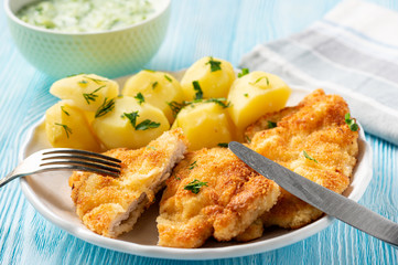Chop pork cutlets , served with boiled potatoes and tzatziki dip. 