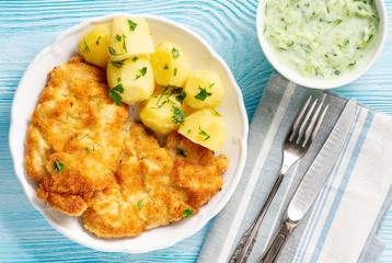 Chop pork cutlets , served with boiled potatoes and tzatziki dip. 