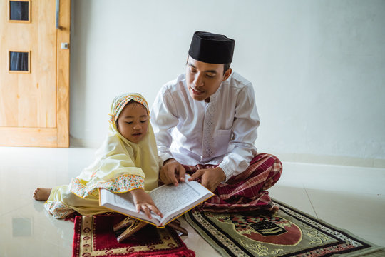 learn how to read qoran. muslim young child with daddy reading holy book of islam