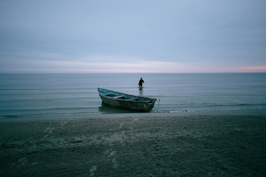 Idyllic picture of calm sea with the fisherman and his boat in the foreground, Baltic sea