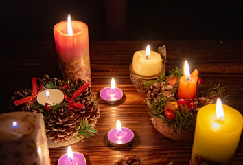 Many burning candles in the dark on a wooden table.