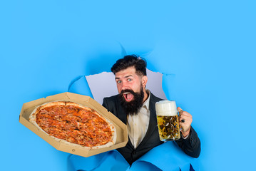 Pizza time. Fastfood. Italian food. Pizza delivery concept. Bearded man with tasty pizza and beer looking through paper hole. Satisfied man with beard and mustache enjoy delicious pizza and cold beer.