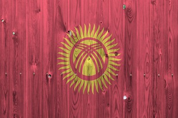 Kyrgyzstan flag depicted in bright paint colors on old wooden wall. Textured banner on rough...
