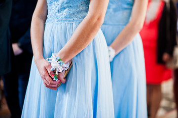 Hands of bridesmaids on blue dresses at wedding.
