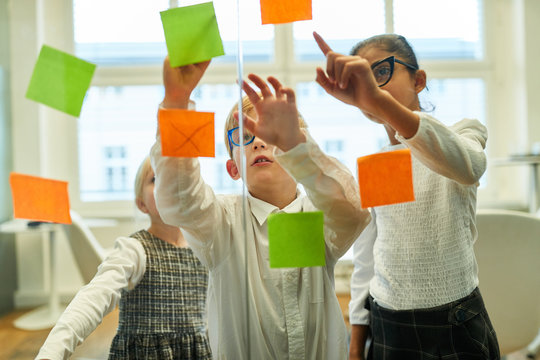 Kinder als Business Team notieren Ideen auf Zettel