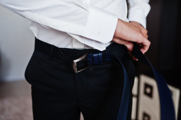 Morning of the groom preparation. Young and handsome groom getting dressed.