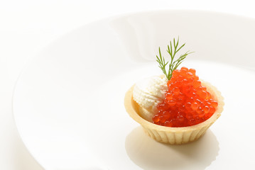 red caviar in a basket of dough with cream cheese on a white plate