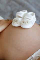 Pregnant woman lying on a bed in the bedroom, dressed in lingerie.