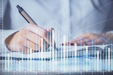 Multi exposure of woman's hands making notes with forex graph hologram. Concept stock market...
