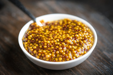 Basic sauce - mustard in a round ceramic dish on a dark rustic background.