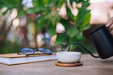Garden reading table, Hand is pouring tea into the teacup, Close-up