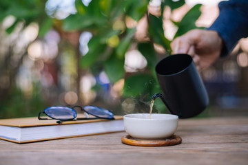Garden reading table, Hand is pouring tea into the teacup, Close-up