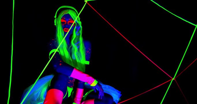 Sexy woman in ultraviolet light is glowing in the dark, bright colors and lights