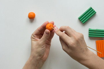 Woman hands making strips with tooth stick on orange ball from polymer clay for create orange fruit