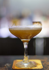 The bartender is lighting a cocktail, a cocktail is lit in a bar