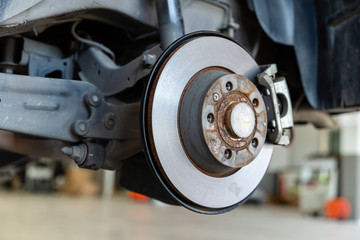 Closeup disc brake of the vehicle damaged , in process of new tire replacement. Car brake repairing in garage