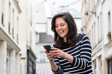 Fototapeta na wymiar smiling woman looking at cellphone in city