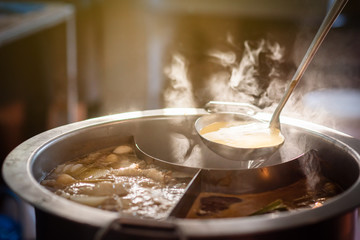 Cooking person in the restaurant is cooking while using the dipper in a large soup pot. And the...