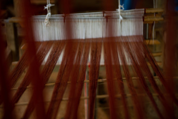 Close up of woman weaving silk from hand weaving machine.   